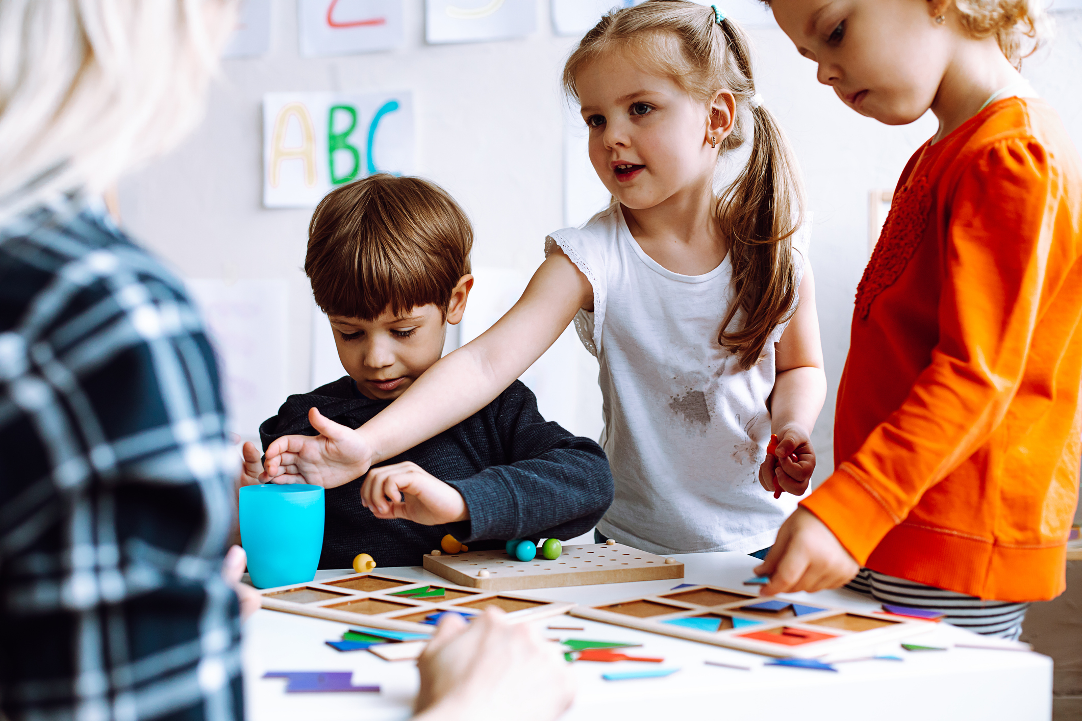 Kinder spielen mit Spielzeug und einer Betreuerin.
